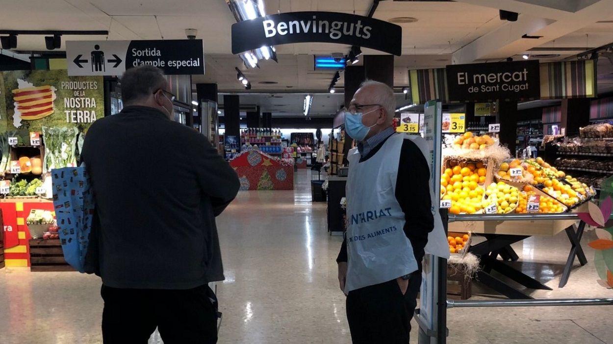 Un voluntari s'adreça a un client a un supermercat de Sant Cugat / Foto: Cugat Mèdia
