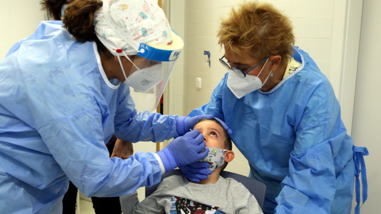 Dues sanitàries li fan un test d'antígens a un nen / Foto: ACN