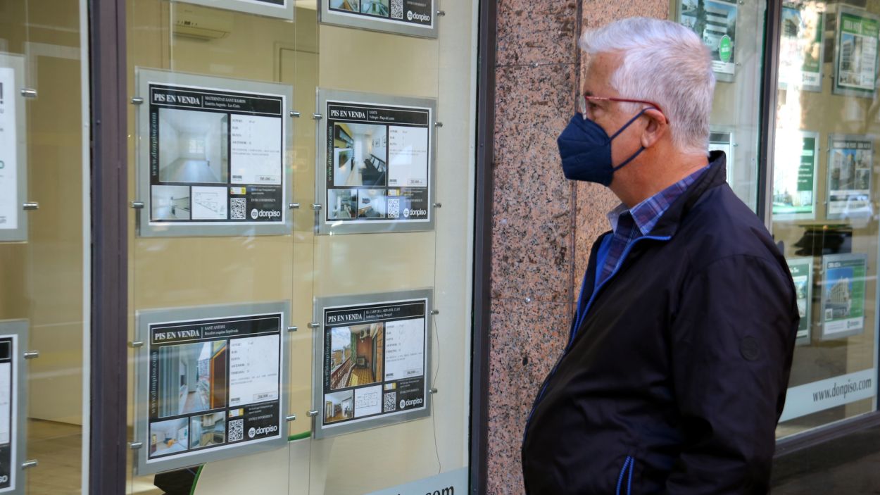 Un home mira cartells amb pisos anunciats a una immobiliària / Foto: ACN