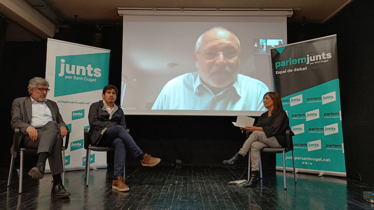 Lluís Puig, a la pantalla; a l'escenari, Jordi Pina, Aleix Sarri i Cristina Paraira / Foto: Cugat Mèdia