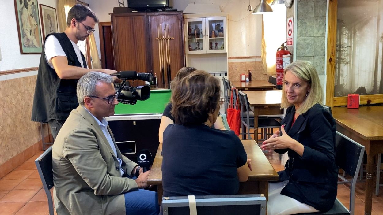 L'alcaldessa, Mireia Ingla, i el presentador Albert Solé conversant amb dues veïnes de Les Planes dins el bar Talismán II / Foto: Cugat Mèdia