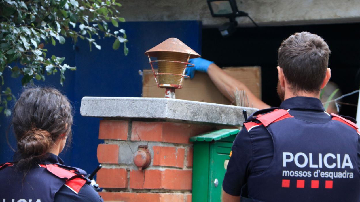 Dos agents dels Mossos d'Esquadra custodien l'entrada d'una casa de les Planes (Barcelona) / Foto: ACN (Laura Fguls)