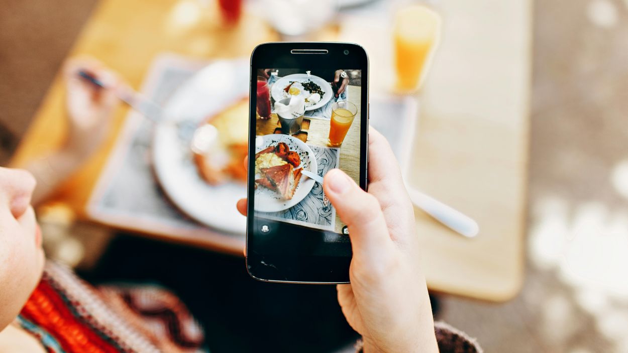 Una persona fent una fotografia amb el mbil a un plat de menjar / Foto: CC0 Pexels Helena Lopes