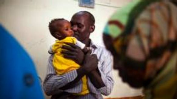 Ibrahim Hassan, besant un nadó, va fugir de la guerra al Darfur per demanar asil a Egipte / Foto: Albert González Farran